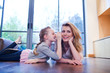 Mother and daughter laying on wooden floor whispering