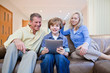 Grandparents on couch watching grandson using digital tablet