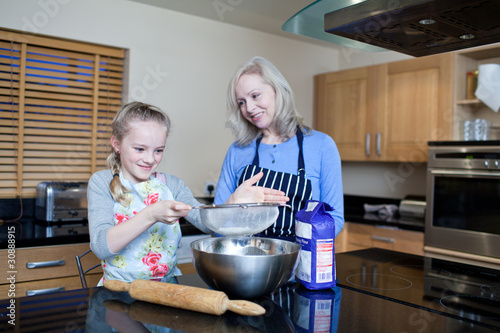 Photo: Grandmother and granddaughter baking in kitchen Grandmother and granddaughter baking in kitchen