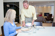 Man serving birthday cake to wife in dining room