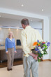 Man surprising his wife with bunch of flowers