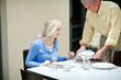 Man serving birthday cake to wife in dining room