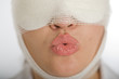 Woman with bandaged face blowing a kiss