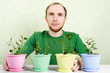 man in green shirt sitting near table with plants in bright flow