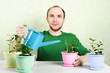 man in green shirt sitting near table and watering plants in bri