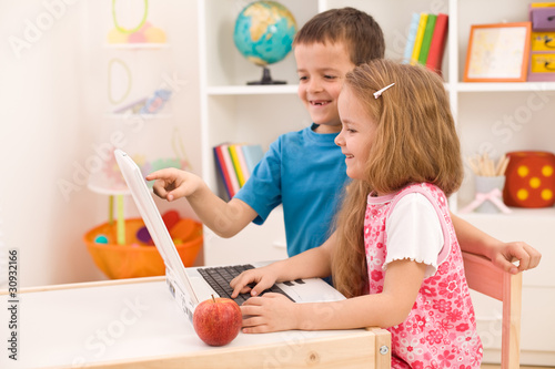 Photo: Kids playing on laptop computer at home Kids playing on laptop computer at home