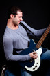 Young man playing guitar isolated on black