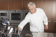 Mid adult chef leans for knife