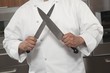 Mid- adult chef sharpens knives
