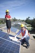 Photo: Two business people on a rooftop next to solar panelling with a set of plans Two business people on a rooftop next to solar panelling with a set of plans