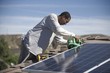 A man on a rooftop working on solar panelling