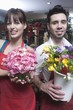 Florists stand holding a bucket of cut flowers and a hydrangea