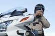 Patrol officer sits on motorcycle looking through pseedometer