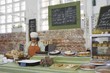 Catering assistant stands in service area of canteen
