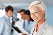 Businesswoman smiling her colleagues standing at back