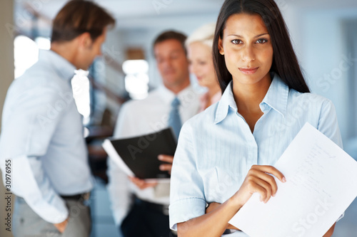 Photo: Confident young female business associate at office Confident young female business associate at office