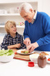 Grandfather And Grandson Making Sandwich In Kitchen