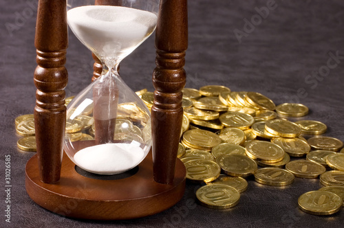 Photo: Hourglasses and coin On a grey background Hourglasses and coin On a grey background