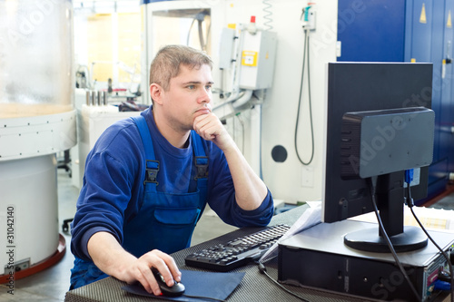 Foto: worker operating CNC machine center worker operating CNC machine center