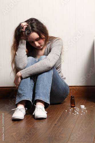 Photo: Teenage girl depressed sitting with pills on floor Teenage girl depressed sitting with pills on floor