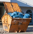 Orangefarbener Container mit Müllsäcken