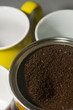 can of ground coffee beans with mugs