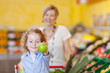 lachendes kind zeigt apfel im supermarkt