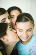 Young female friends kissing younger girl's cheek