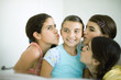 Young female friends kissing younger girl's cheeks