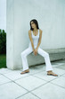 Woman sitting on bench, looking away, full length