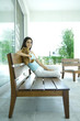 Young woman sitting on bench, holding teddy bear, full length portrait