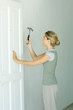 Woman hammering nail into door