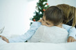 Photo: Mother sitting on sofa, holding boy in arms, Christmas tree in background, boy holding star Mother sitting on sofa, holding boy in arms, Christmas tree in background, boy holding star