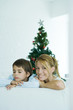 Photo: Boy and mother on sofa, Christmas tree in background, woman smiling at camera, boy frowning Boy and mother on sofa, Christmas tree in background, woman smiling at camera, boy frowning