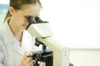 Young female scientist looking through microscope