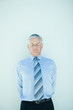 Mature businessman standing, hands behind back, eyes closed