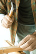 Man hammering nail into piece of wood, close-up of hands