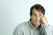 Man leaning face against hand, looking grumpy