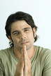Man pleading with hands together, looking at camera, portrait