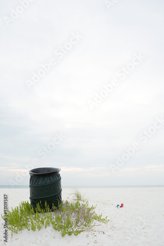 Photo: Garbage can on beach, litter lying on the ground nearby Garbage can on beach, litter lying on the ground nearby
