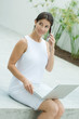 Woman sitting, using cell phone, holding laptop computer on lap