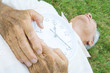 Senior man lying on grass, holding clock, cropped view