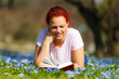 frau liegt in der blumenwiese und liest ein buch