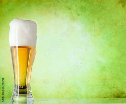 Photo: Glass of beer on a green background Glass of beer on a green background