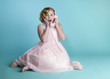 Foto: Cute little girl talking on a vintage pink telephone Cute little girl talking on a vintage pink telephone