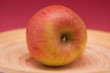 Roter Apfel mit rotem Hintergrund auf Holzteller Roter Apfel mit rotem Hintergrund auf Holzteller