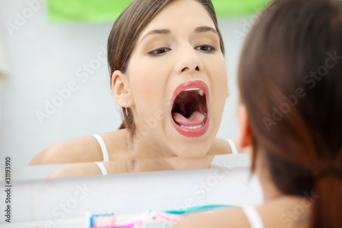 Photo: Young beautiful caucasian woman checking her throat Young beautiful caucasian woman checking her throat