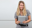 Beautiful blond woman using touchpad on grey background