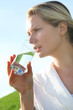 Photo: Woman drinking natural water in green field Woman drinking natural water in green field