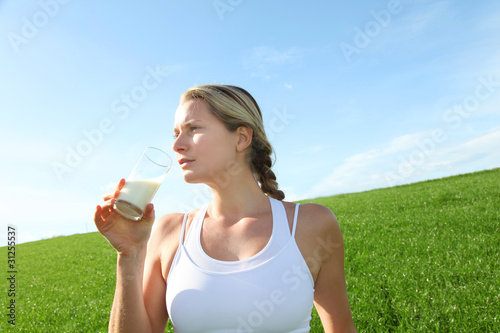 Photo: Beautiful blond woman drinking milk in countryside Beautiful blond woman drinking milk in countryside